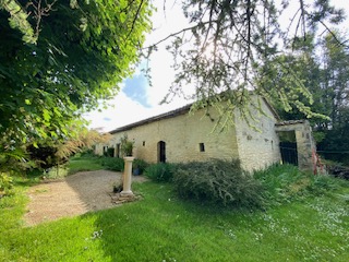Grange en pierre et allée bordée de verdure
